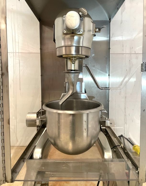 used Hobart model A-200-D Commercial 20 Quart Dough Mixer with Stainless Steel housing. SN: 1499102, Electrical: 115V, 60Hz, 8.2Amps, 1 Phase. Includes dough hook.  On portable cart with plexiglass enclosure. 